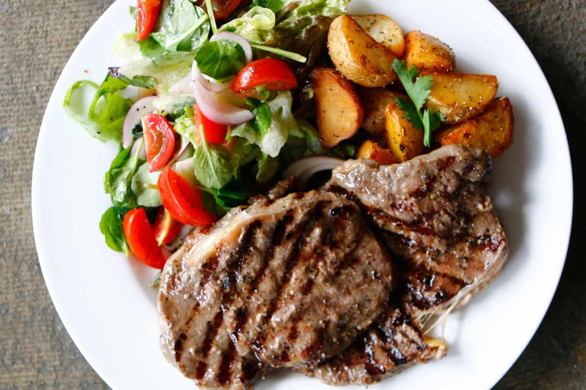 Chuck steak marinated with olive oil, garlic, rosemary, and soy sauce in a glass dish