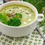 A bowl of gluten-free broccoli cheddar soup garnished with extra cheese, delivering a creamy and cheesy flavor