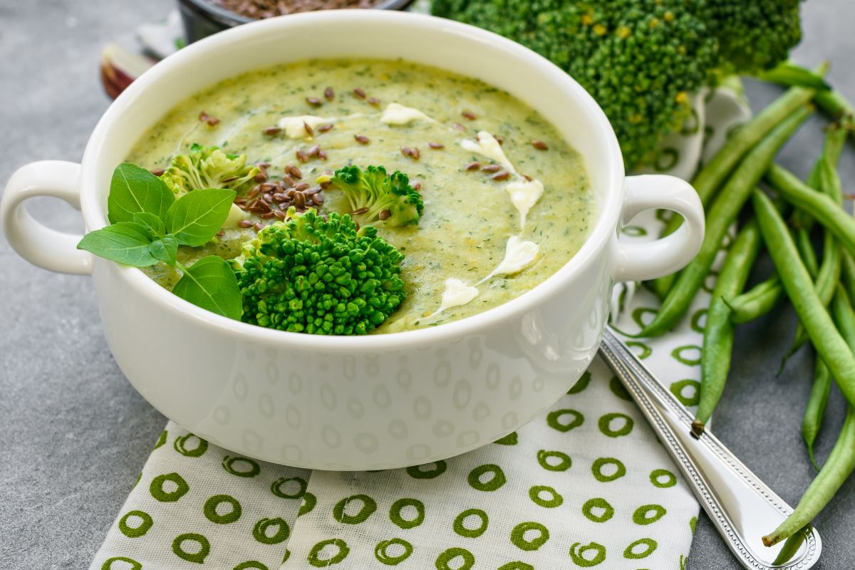 A bowl of gluten-free broccoli cheddar soup garnished with extra cheese, delivering a creamy and cheesy flavor