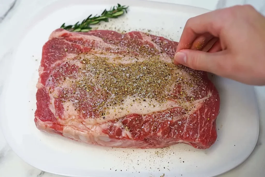 Close-up of a raw Ribeye Roast Recipe, showing marbling and fat cap, ready for seasoning.