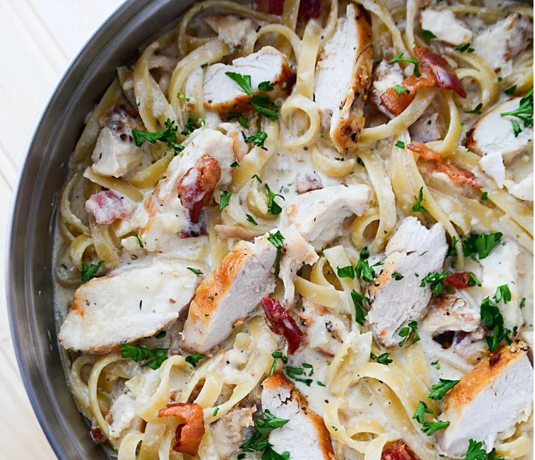 Creamy chicken pasta with bacon in a bowl, garnished with parsley.
