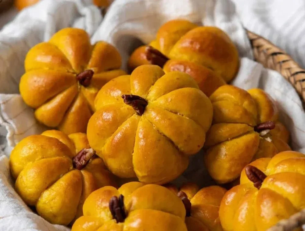 Freshly baked pumpkin dinner rolls, golden brown and fluffy.