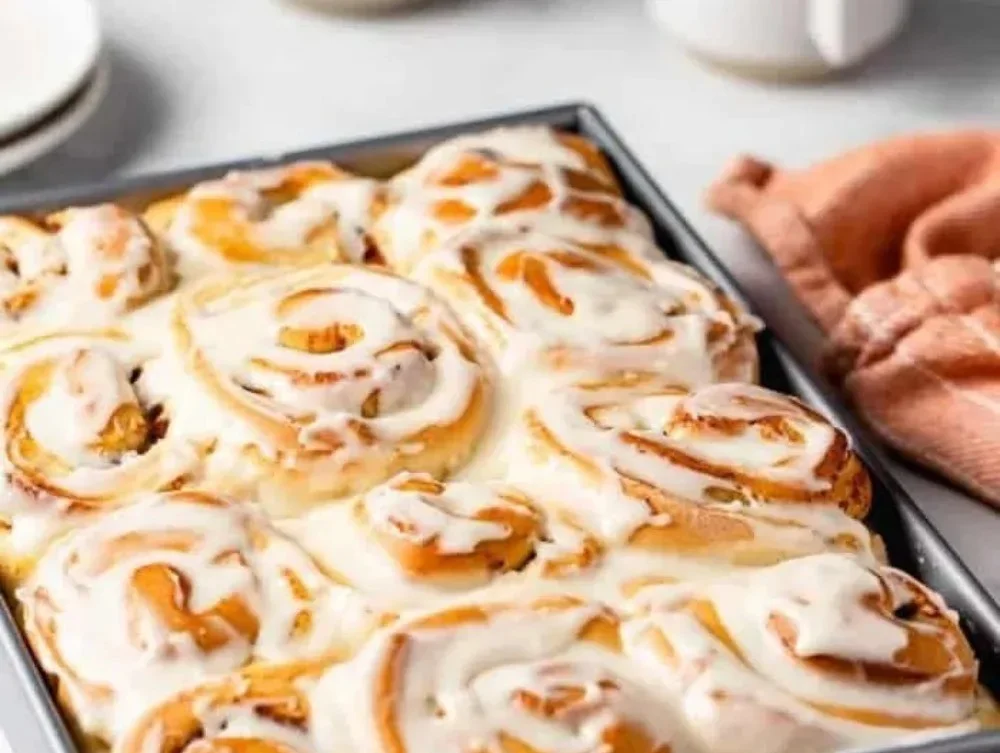 Plate of freshly baked Pumpkin Spice Cinnamon Rolls with icing on top